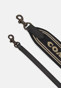 Czarny pasek ze skóry i tkaniny z brązowymi metalowymi klipsami. Pasek ma teksturowaną powierzchnię i beżowe logo z paskami.