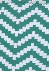 Grüner und weißer Stoff mit einem Zickzackmuster und strukturierten Linien, die ein geschichtetes Aussehen erzeugen. Weiches und elastisches Material.