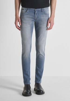 Light blue denim jeans with a slim fit, featuring subtle fading and five pockets. Paired with black ankle boots. Smooth texture.