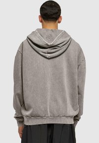 Gray cotton hoodie with a kangaroo pocket, drawstring hood, and ribbed cuffs, features a relaxed fit and subtle texture.