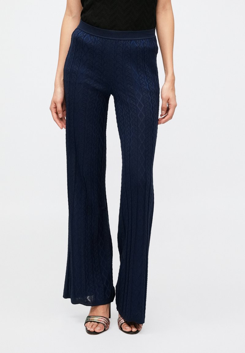 Tmavomodré rozšírené nohavice z textúrovaného pleteného materiálu so vzorom diamantu, s elastickým pásom a uvoľneným strihom.