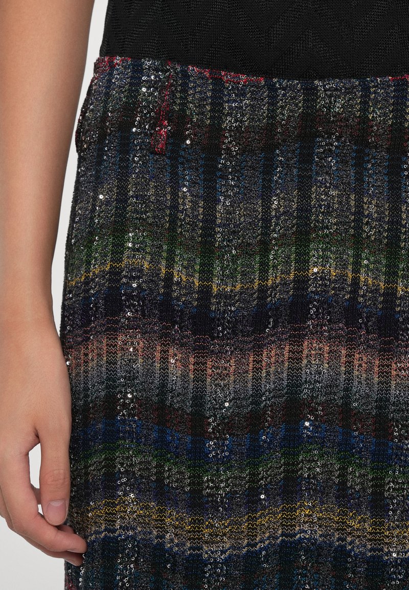 Jupe en tricot à sequins multicolores avec un motif à rayures ondulées. Le tissu présente diverses textures, avec des accents scintillants partout.