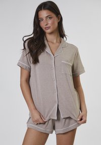 Gestreiftes Kurzarm-Pyjama-Set in Beige und Weiß, bestehend aus einem knöpfbaren Oberteil mit Tasche und passenden Shorts mit weißem Saum.