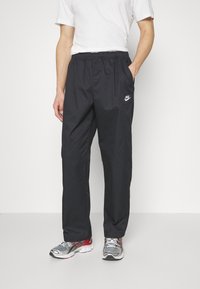 Svarta, lätta Nike träningsbyxor med elastisk midja, sidfickor och en liten vit logotyp på vänster sida. Har raka ben.