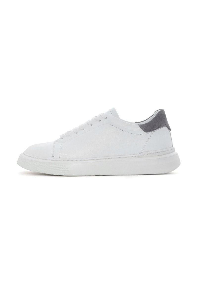 Baskets blanches à lacets avec une tige en cuir lisse, présentant un accent de talon en suede gris et une semelle en caoutchouc texturée.