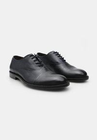Scarpe eleganti in pelle nera con un design raffinato, dotate di una tomaia liscia, punta rotonda e chiusura con lacci a sei forellini. Suola strutturata.