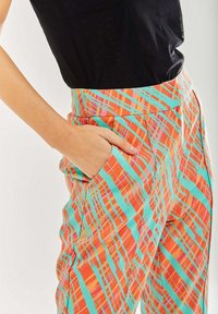 Colorful plaid trousers featuring orange, turquoise, and pink stripes, with a fitted waistband and side pocket detail.