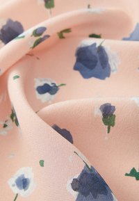 Țesătură de culoare roz deschis, cu un model floral ce include flori albastre și albe, și frunze verzi, având o textură moale și netedă.