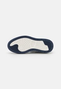 Nike sneaker sula med en marinblå gummibas, med vita spår och texturerade mönster för grepp och hållbarhet.