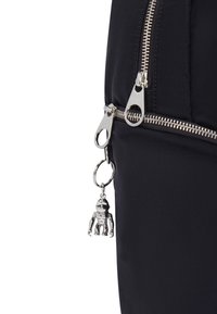 Black nylon backpack featuring a silver zipper with dual pulls and a robot-shaped charm attached to the zipper.