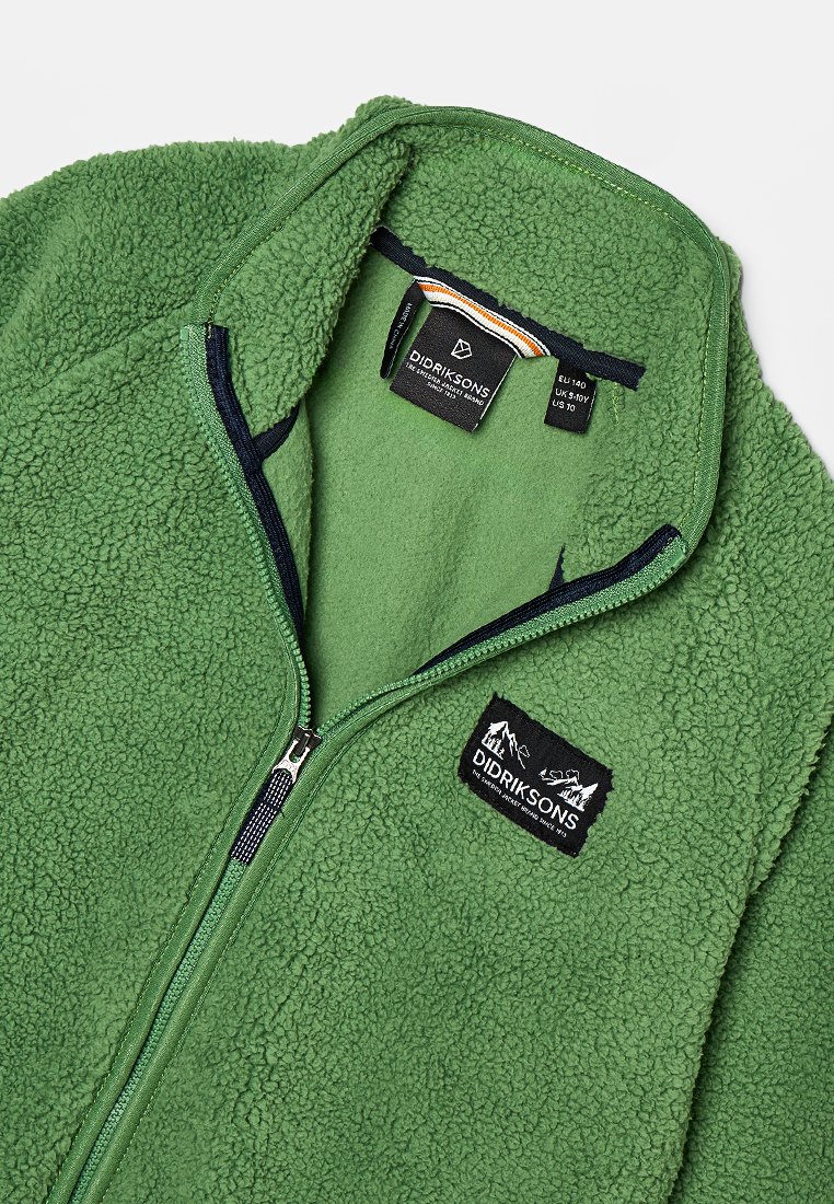 Groene fleecejack met een rits aan de voorkant, hoge kraag en een zwart logo-embleem. Zachte textuur met contrasterende marineblauwe accenten en labeldetails.
