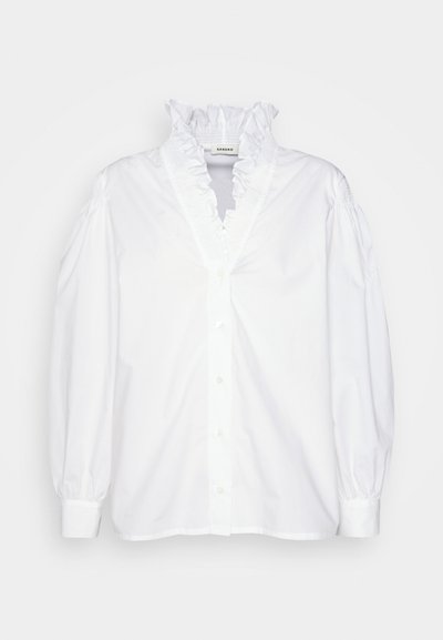 Λευκό πουκάμισο με ρυτιδωτό γιακά, μακριά φουσκωτά μανίκια και υφασμάτινη υφή. Διαθέτει άνετη εφαρμογή και μπροστινό κούμπωμα με κουμπιά.