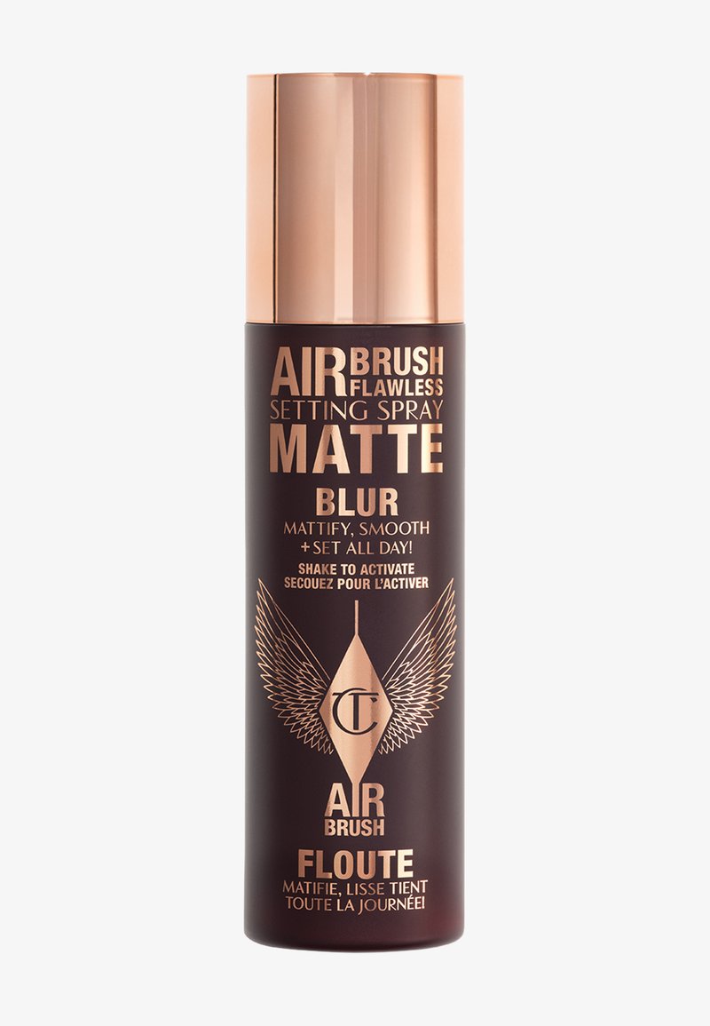 Flacone spray cilindrico di colore nero opaco con un tappo metallico color oro rosa. L'etichetta presenta un testo oro scuro e un motivo di ali, indicante uno spray fissante.