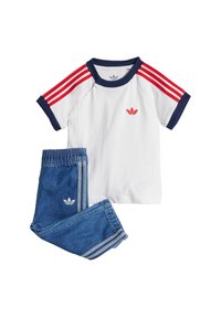 Balta marškinėliai su tamsiai mėlynu apvadu ir raudonomis petnešomis, derinami su mėlynais džinsais, turinčiais šonines juosteles ir logotipo detalėmis.