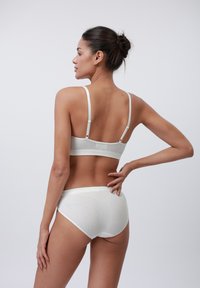 Bralet alb cu nervuri, cu bretele ajustabile și chiloți asortați cu talie înaltă. Material moale cu o textură netedă și un design minimalist.