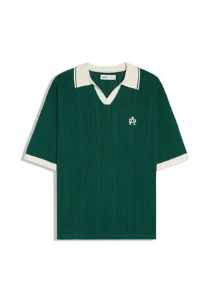 Polo en maille à manches courtes vert foncé avec col blanc, poignets blancs, motif texturé et petit logo blanc brodé sur la poitrine.