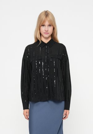 Black button-up shirt with vertical sequin stripes, long sleeves, and two chest pockets; paired with a blue skirt. Smooth texture.