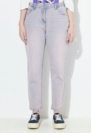 Helles rosa, hochgeschnittene Jeans mit geradem Schnitt, die fünf Taschen und dezente Verwaschungen aufweisen. Kombiniert mit navyblauen Turnschuhen.