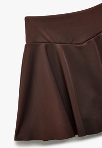 Brun udvidet nederdel lavet af et glat, strækbart stof. Taljen er tætsiddende, og stoffet har en blød tekstur med en subtil glans.