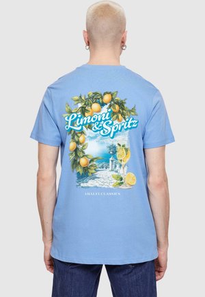 Light blue cotton t-shirt featuring a colorful graphic of lemons and a drink, with the text "Limoni & Spritz" and a coastal scene.