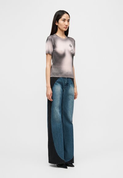 Πλεκτό t-shirt σε γκρι διαβάθμιση, με κοντά  μανίκια και κεντημένη λεπτομέρεια. Τζιν παντελόνια με φαρδιά γραμμή σε ξεβαμμένο μπλε και μαύρο χρώμα με χαρακτηριστικά πάνελ.