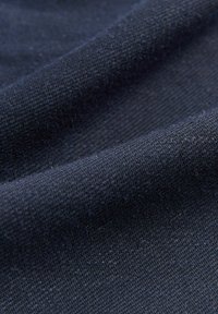 Námořnická modrá tkanina s jemným, texturovaným vazem, vykazující mírné variace v odstínu a hladký, jemný povrch.