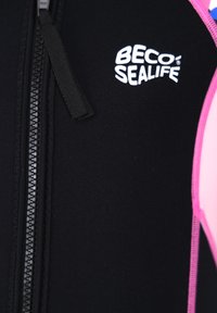 Wetsuit featuring black neoprene material with a pink accent. Zipper detail with a branded logo in white on the chest area.