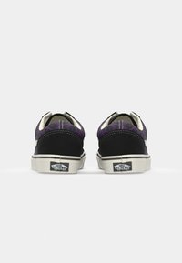 Sorte og lilla sneakers med en overdel i stof har et leopardmønster, kontrasterende hvid syning og en gummisål.