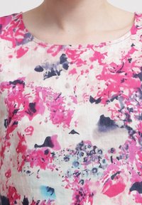 Tissu imprimé floral présentant des nuances de rose, de violet et de bleu sur un fond clair, avec une texture lisse et un design à encolure large.