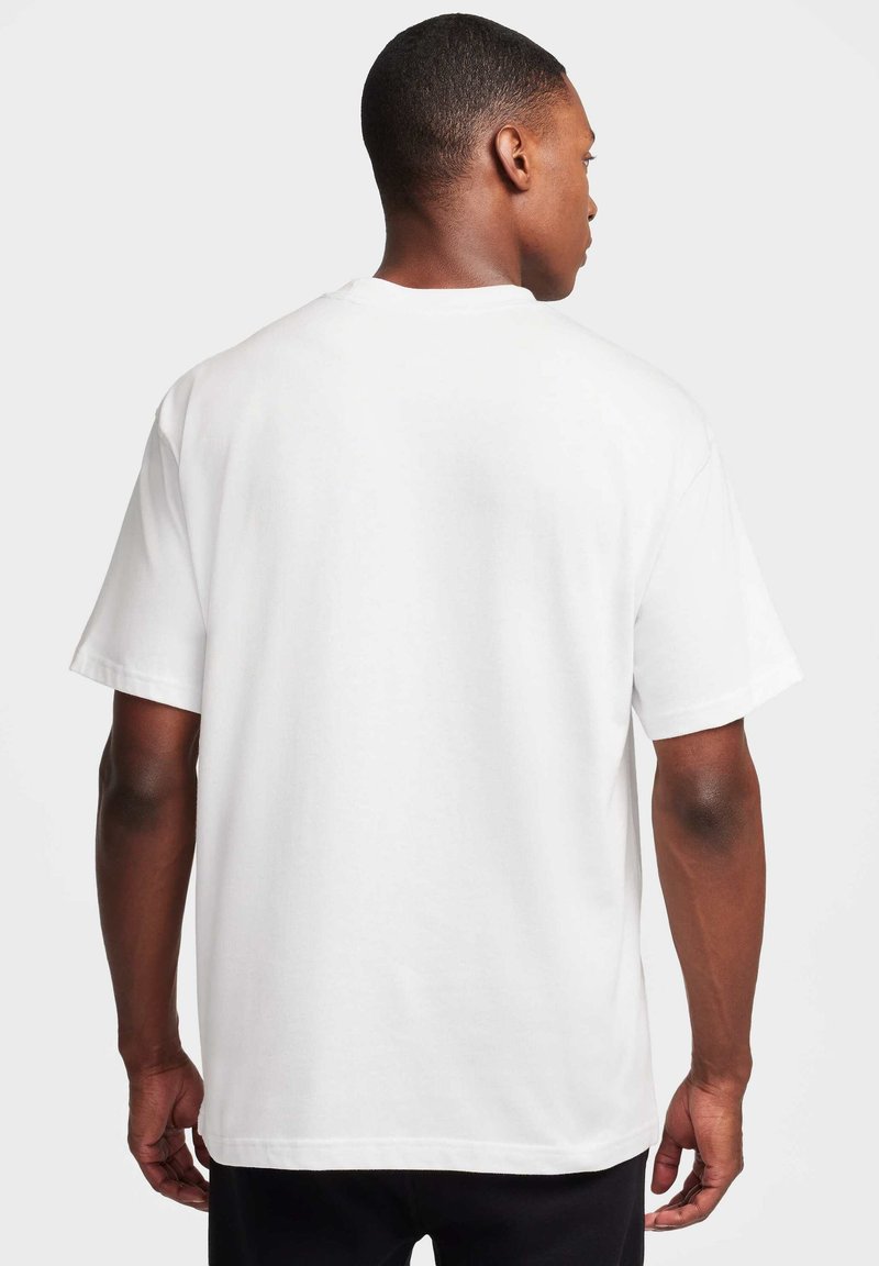 Biała bawełniana koszulka z krótkimi rękawami, luźny krój, okrągły dekolt i gładka tekstura, przedstawiona z tyłu. Brak widocznych logo lub wzorów.