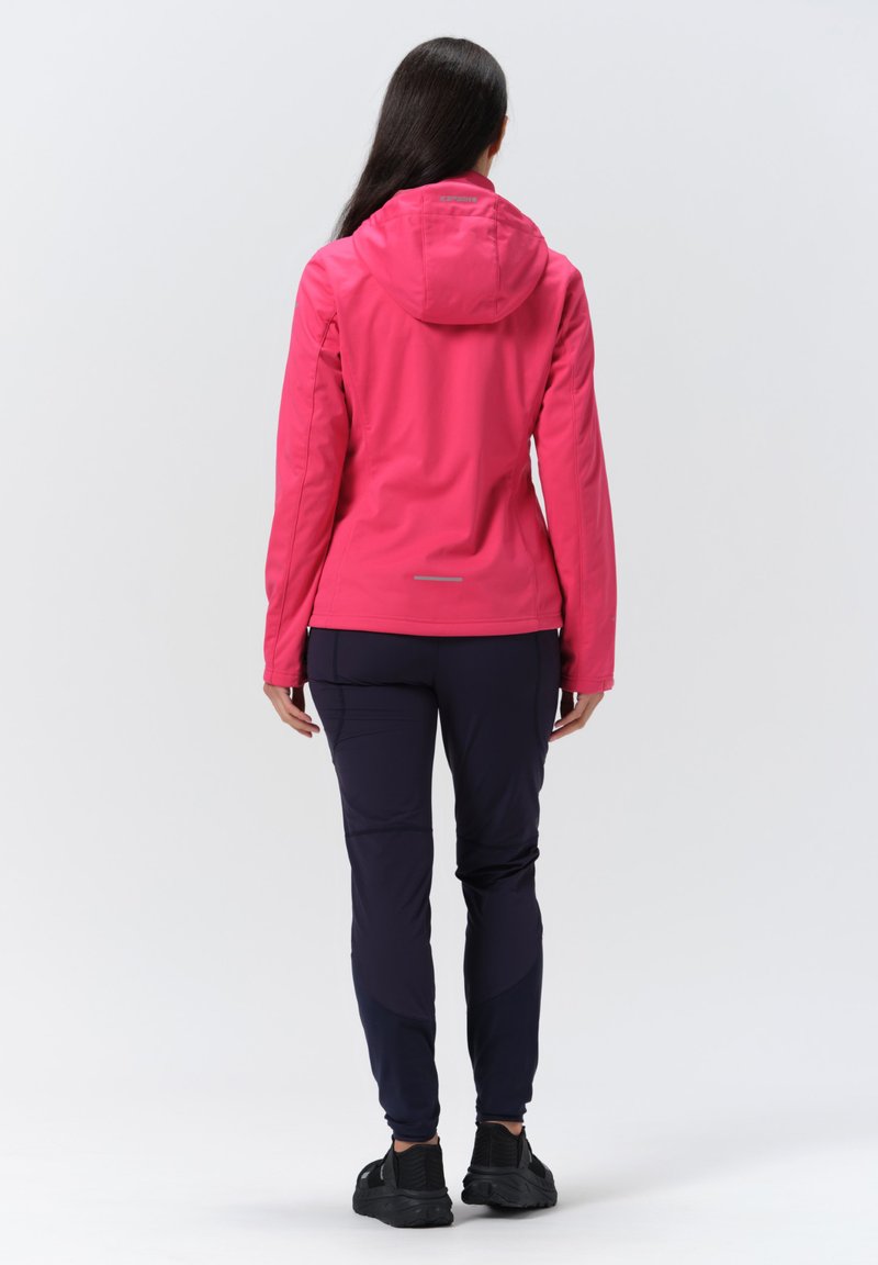 Fuksjowa wodoodporna kurtka z kapturem, o dopasowanym kroju i odblaskowych akcentach, w połączeniu z granatowymi spodniami i czarnymi butami sportowymi.