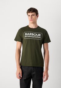 Olivově zelené bavlněné tričko s bílou grafikou "BARBOUR INTERNATIONAL" na přední straně, kulatým výstřihem a krátkými rukávy.
