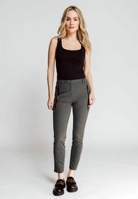 Dark gray fitted pants with zippered pockets and a textured fabric, paired with a black tank top and chunky black shoes.