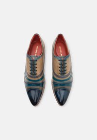Scarpe di pelle con un mix di colori marrone chiaro, teal e navy, con punta appuntita e lacci decorativi. Texture liscia e lucida.