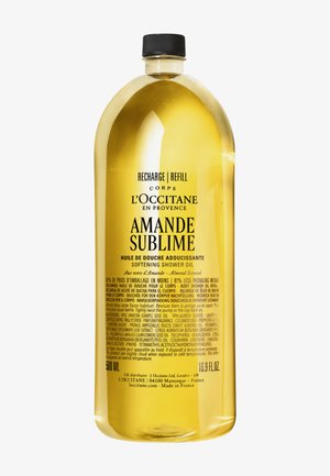 Recharge en huile de douche adoucissante à l'amande parfumée L'Occitane Amande Sublime, 500 ml, bouteille transparente avec bouchon noir.