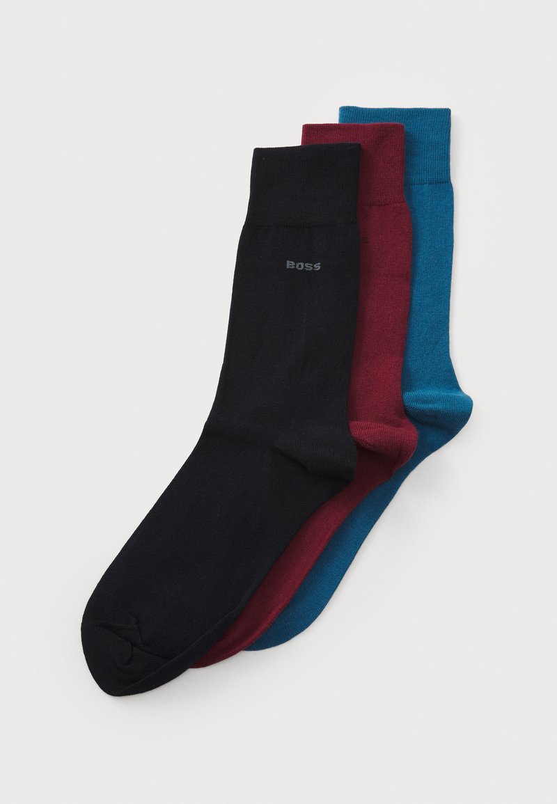 Drei Paar Socken in Schwarz, Burgunder und Blaugrün. Hergestellt aus glattem Material mit einem gerippten Bündchen und dezenter Markenkennzeichnung auf der schwarzen Socke.