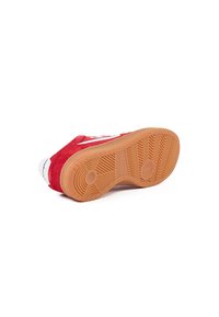 Sneaker rossa in suede con suola in gomma, caratterizzata da un logo bianco e un motivo di battistrada testurizzato sulla parte inferiore per una migliore aderenza.