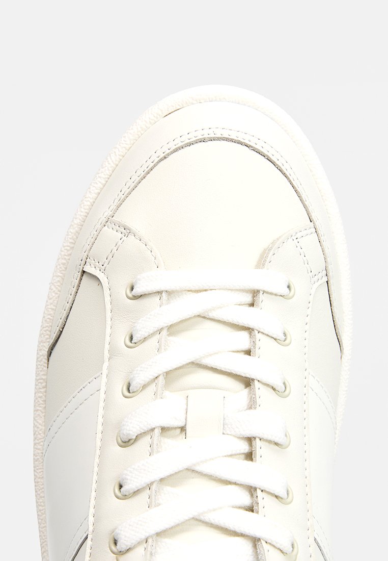 Witte lederen sneaker met een klassiek vetersysteem, featuring een textuur rubberen zool en subtiele stikdetails langs de zijkanten.