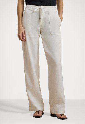 Pantaloni larghi in lino color beige chiaro con vita regolabile, dotati di due tasche frontali e una vestibilità comoda. Sandali piatti completano il look.