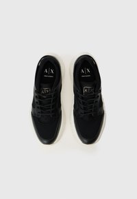 Čierne tenisky Armani Exchange s bielymi podrážkami, zvrchná časť zo sieťoviny a kože, čierne šnúrky a zlaté logo A|X na jazyku, pohľad zhora.