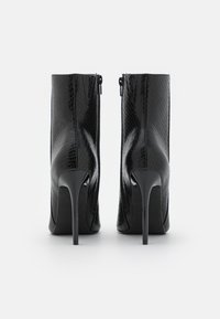 Czarne botki za kostkę na wysokich szpilkach, wykonane z teksturowanej syntetycznej skóry węża. Posiadają elegancki zamek błyskawiczny z tyłu.