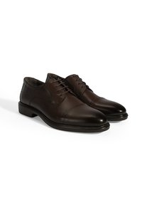 Bruine leren dresschoenen met een gladde afwerking, voorzien van een ronde neus en subtiele stikdetails, gemonteerd op een lage, duurzame zool.