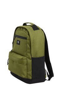 Green fabric backpack with a front zip pocket, black bottom section, and adjustable straps. Features a logo patch on the front.