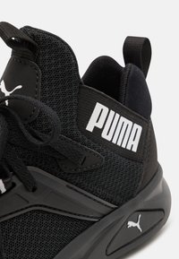 Chaussure de sport noire avec une tige en mesh texturé, une semelle en caoutchouc et un logo Puma en blanc bien visible sur le côté et le talon.