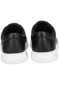 Schwarze Ledersneaker mit einer glatten Oberfläche, weißen Gummisohlen und einem gesteppten Design entlang der Rückseite. Enthält ein Markenlogo auf der Sohle.