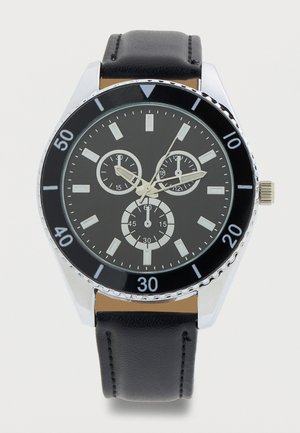 Herrenuhr mit schwarzem analogem Zifferblatt, Lederarmband, drei Hilfszifferblättern, silbernem Gehäuse und Minutenmarkierungen auf der Lünette.