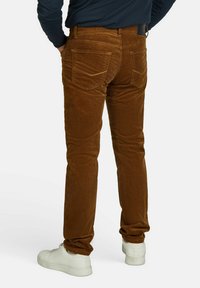 Bruine corduroy broek met een slim fit, voorzien van een vijf-pocket ontwerp en een subtiele structuur. Draag het met witte sneakers.