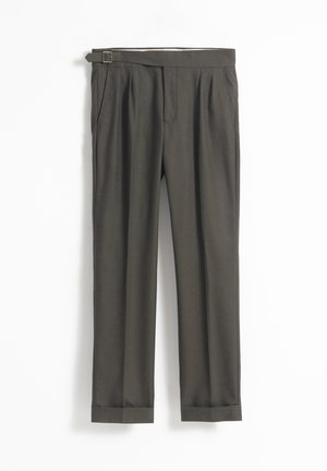 Pantalones ajustados de color verde oscuro con cinturón, que cuentan con un frente plisado y dobladillos con puños. Textura suave y acabado pulido.