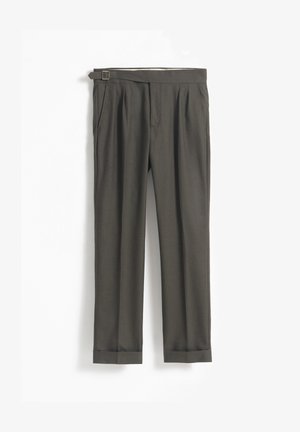 Pantalones ajustados de color verde oscuro con cinturón, que cuentan con un frente plisado y dobladillos con puños. Textura suave y acabado pulido.