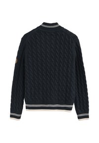 Marinblå kabelstickad tröja med vit randig krage, mudd, fåll och en liten guldfärgad och svart patch på högra ärmen.